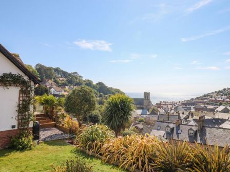 A view of a house with a garden and sea in the background at Devona Beer