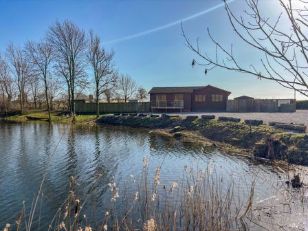 A water body with a building and trees at Star Carr Lakes