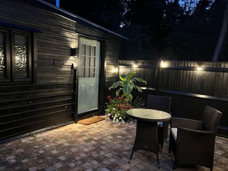 An outdoor seating area with a table and chairs at Woodland Lodge The Snug Filby