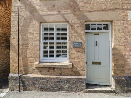 A door and window on a brick wall at Tea Tree Cottage in Chipping Campden