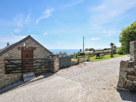 An outdoor area with a stone cottage and sea view at Casa Mia in Porthpean near St Austell