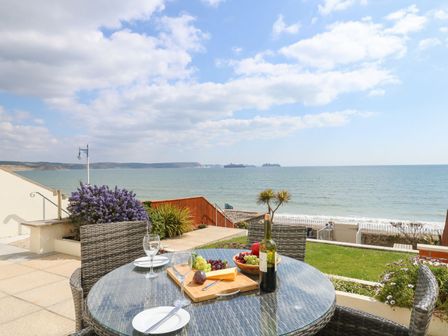 An outdoor dining area with a table and chairs overlooking the sea at Ocean Wave in Greenhill