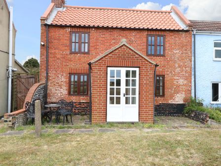 An outdoor view of a brick house with a patio and garden at Mabby Great Yarmouth