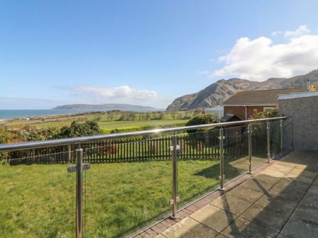 A view from a balcony showing grass and mountains at Orme View in Penmaenmawr