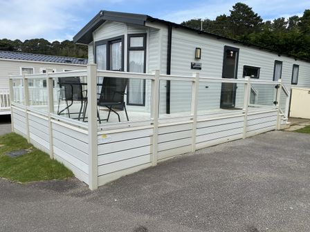 A caravan with a deck and chairs at WW15 Plot in Newquay