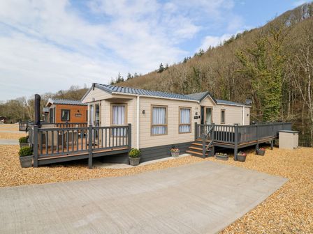 A mobile home with a deck and steps at 33 Woodpecker Lodge in Llanarth