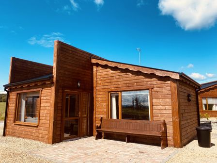 A wooden cabin with a bench outside at No 5 Enniskillen