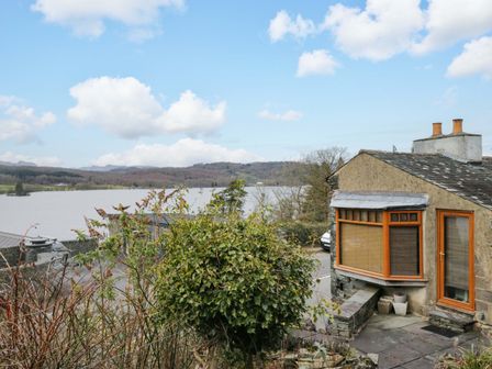 A house near a lake with trees and bushes at Wilders Wood in Windermere