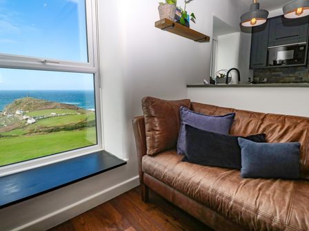 A living room with a sofa and window view at Cape View in Cape Cornwall near St Just