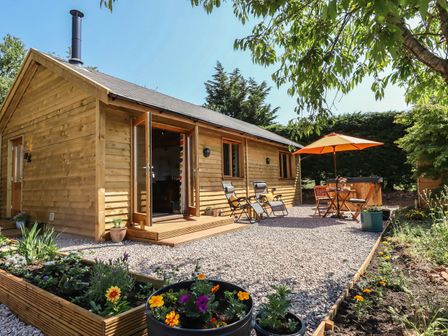 An outdoor seating area with a table and chairs at Nelli Lodge at Mile End in Crediton