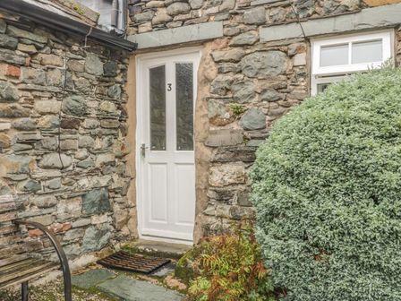 An entrance with a white door and stone wall at Cottage 3 in Keswick
