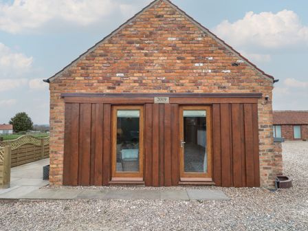 An outdoor view of a brick building with wooden and glass doors at Bumble Bee Lodge in Filey