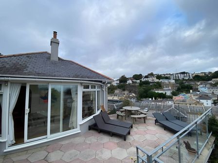 An outdoor area with deck chairs and a table at 4 Bed House-Sleeps 8-Parking-Pets-MarinaSeaView in Torquay