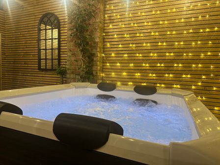 A hot tub surrounded by a wall with lights at Blacksmiths Retreat in York