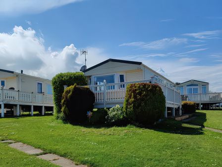 A mobile home with grass and a pathway at Reighton Sands Holiday Park - Holiday Accommodation 17652 Filey