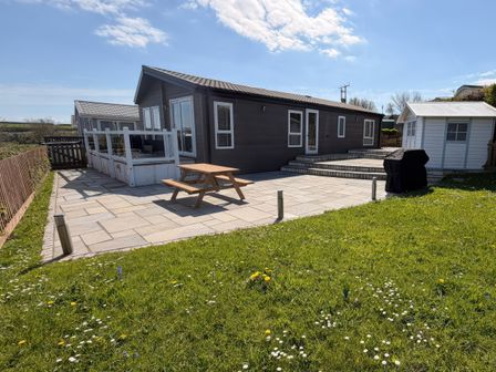 A patio area with a table and chairs at Wernlas Lodge in Oxwich