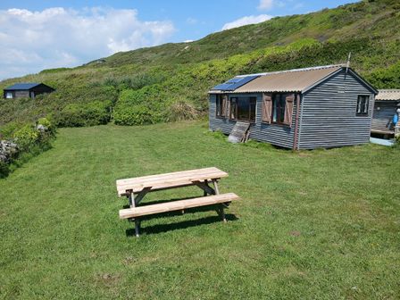 A picnic table and shed in a grassy area at The Cabin