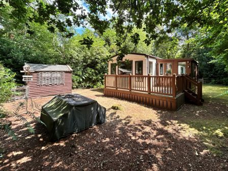 A property with a deck and garden shed at The But n Ben - Kelling Heath Holiday Park in Holt