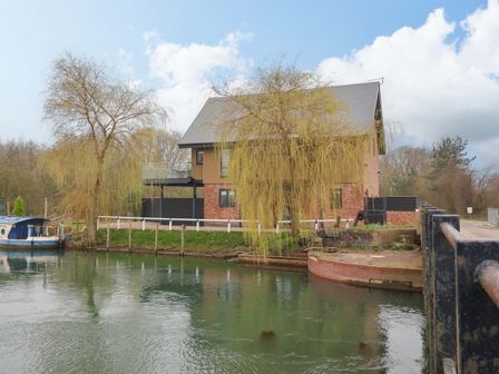 A house by the water with a boat at Swing Bridge Cottage in