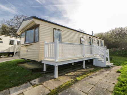 A mobile home with a deck and steps at Ger Y Mor in New Quay