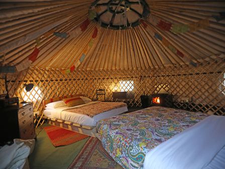 A bedroom with two beds and a stove at Hapus Yurt - Two Beautiful Yurts and Barn Cottage