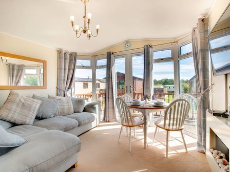 A living room with sofa and dining table at Pet-friendly lodge with hot tub near the coast