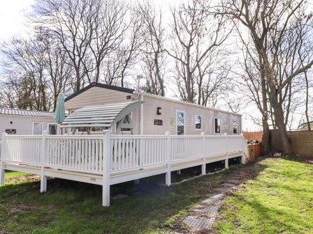 A caravan with a deck and umbrella at Sunflower Retreat, Caravan 61