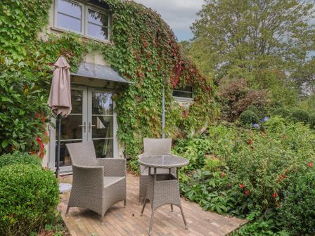 A garden with a table and chairs at The Bothy at Lewis Cottage in Spreyton