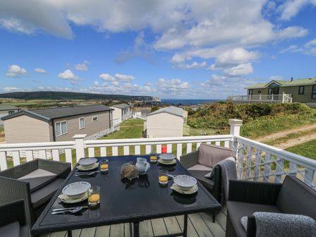 A patio area with a table and chairs overlooking the landscape at Swanny View in Swanage