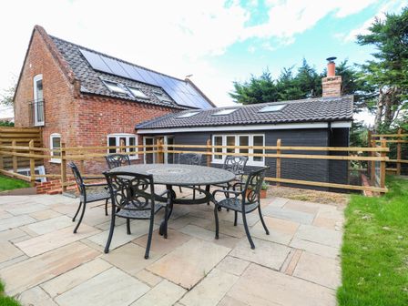 A patio area with a table and chairs at Bramley Cottage in Worlingham