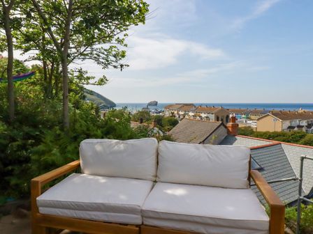 A sofa with a view of the sea and houses at 18 Tregea Terrace in Portreath