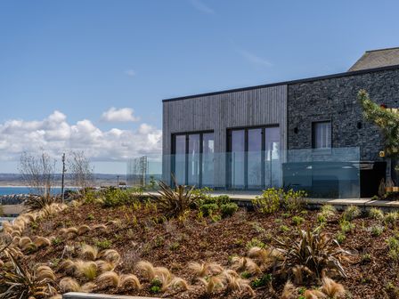 A house with a glass railing and stone wall at Hidden 13- Skyline Terrace St Ives