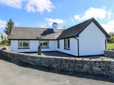 A house with a stone wall and windows at Cahir Cottage in Ballinrobe, County Mayo