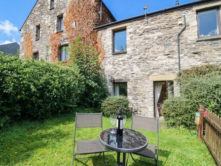 A garden with a stone building and table set at Rooftops in Lindale