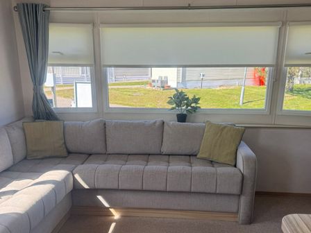 A living room with a sofa and a plant at Caravan - Sleeps 6 - Parking in Lossiemouth