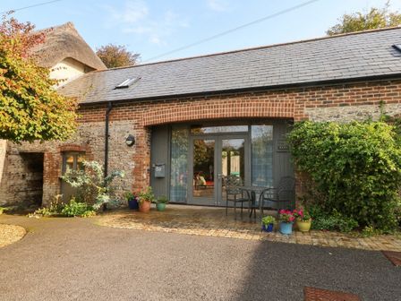 A building entrance with seating and plants at Frome Gazey Barn in Frampton