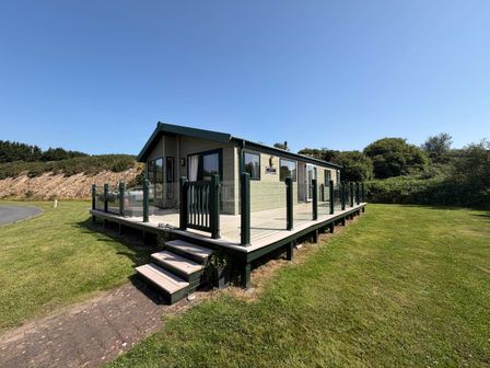 A house with a deck and stairs in an outdoor setting at The Stables Pwllheli