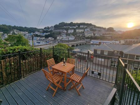 An outdoor seating area with a table and chairs overlooking the harbor at Looe Cottage Seaside views log fire sleeps 4, Looe