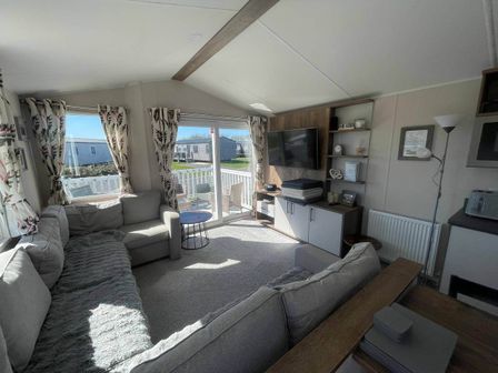 A living room with a television and seating area at Near Flookburgh