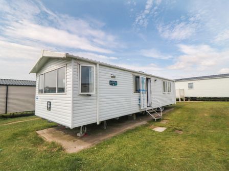 A mobile home with stairs and grass area at 42 Oak Green