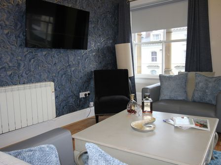 A living room with a television and seating at Cornerhouse Apartment 2 in Llandudno