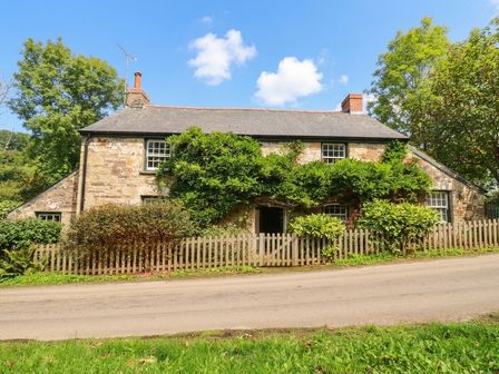 A stone house with a fence and trees at The Homestead in