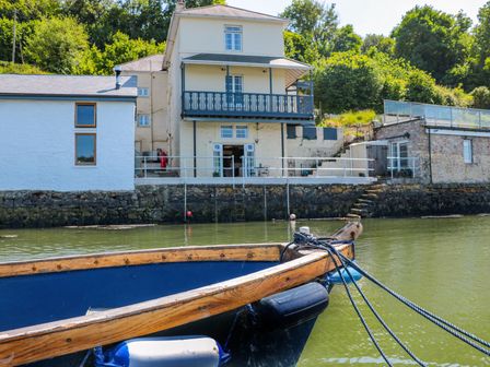 A house with a balcony and boat in the water at Shipwrights in Brixham