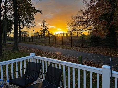 An outdoor area with chairs and trees during sunset at Wl34 Caravan Haggerston Castle Private Decking Haggerston
