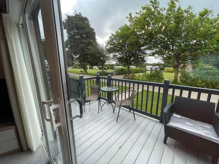 An outdoor area with a table and chairs on a deck at