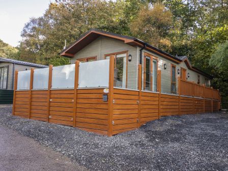 A vacation lodge with a wooden fence at Bella's Retreat in 19 Pony Meadow, White Cross Bay near Windermere