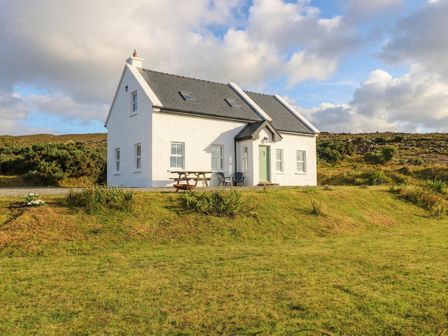 A house with a table and chairs outside at Doughbeg Beach Cottage