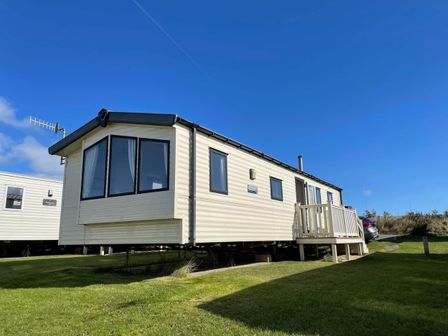 A caravan with a wooden deck at Blue Dolphin Holiday Home in Gristhorpe
