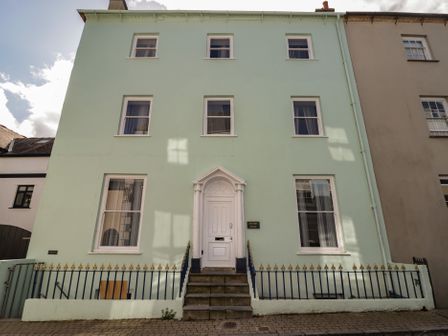 A building with a green exterior and white door at Flat 1 in Tenby