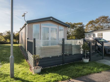 A mobile home with a deck and plants at 19 Finch in